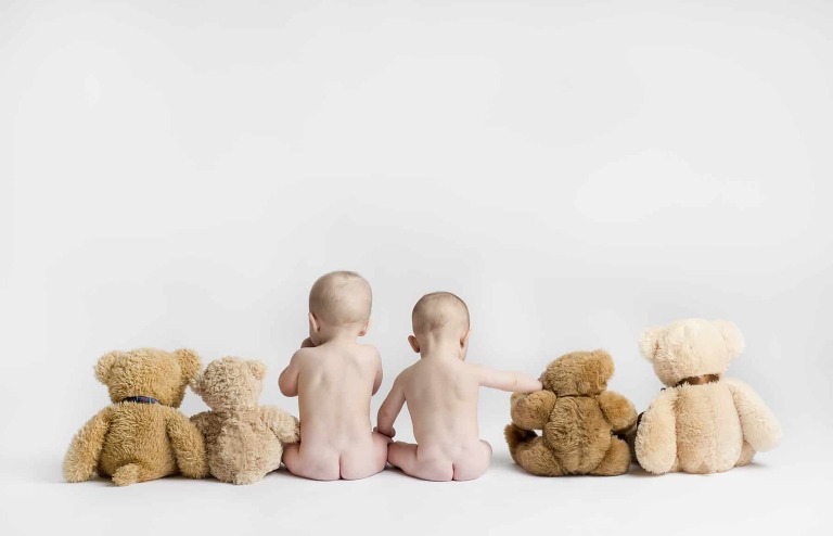 twins sitting with bears with the bare butts