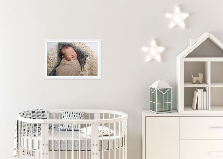 framed picture of newborn boy on wall over crib