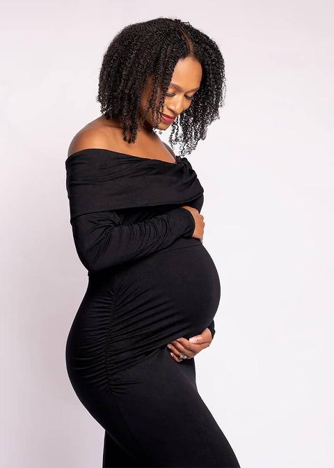 pregnant African American woman in black dress looking down