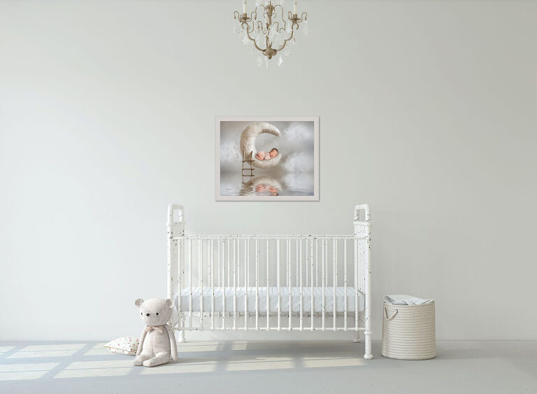nursery view with white crib and framed picture of baby girl laying on a moon prop