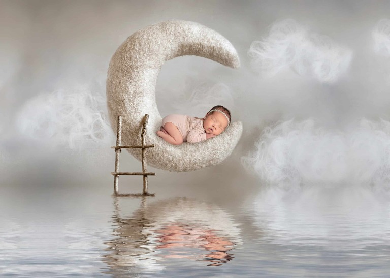 newborn baby girl in moon prop with reflection in water