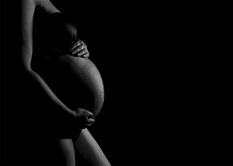 maternity image with rim lighting to show form of belly on black background
