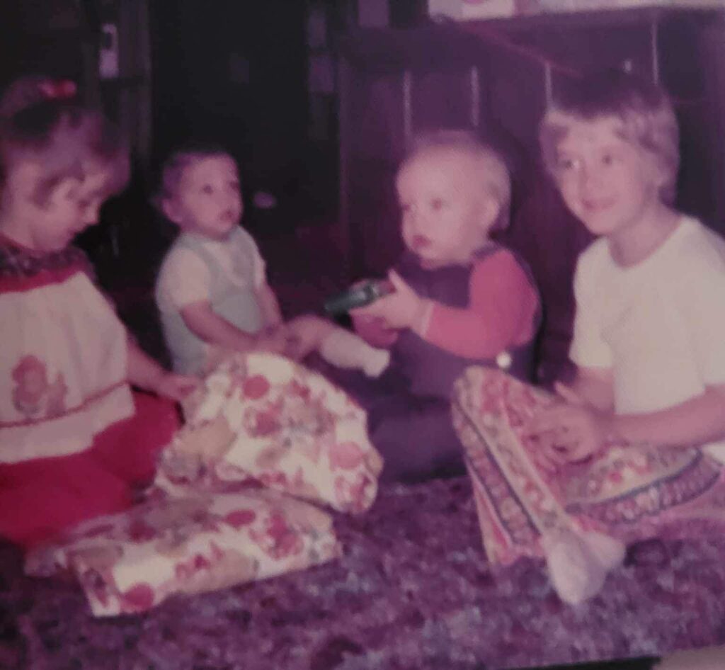 4 children sitting on the floor opening presents in the 1970's