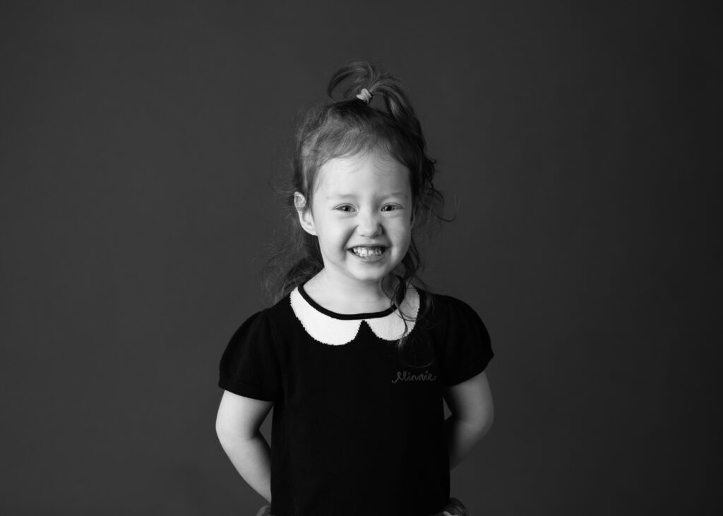 young girl with curly hair with a giant smile on her face