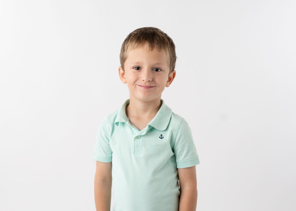 young boy in light green shirt with a smirk