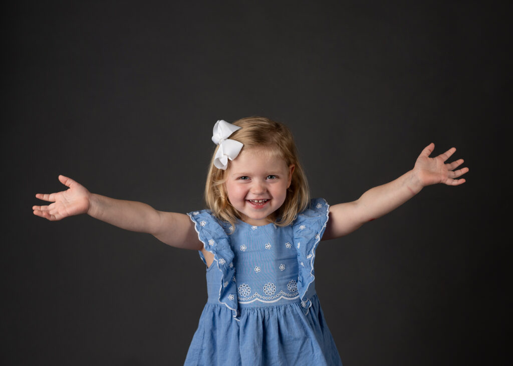 young blonde girl with her arms outstretched in excitement