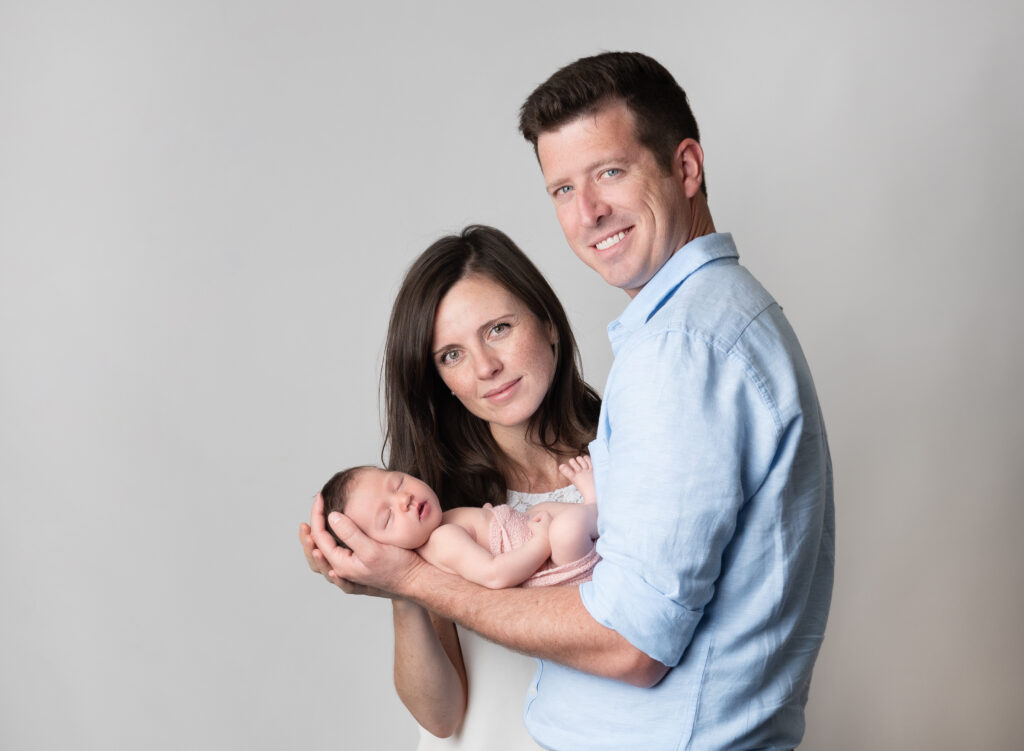 new parents posing for newborn photos with their new baby girl