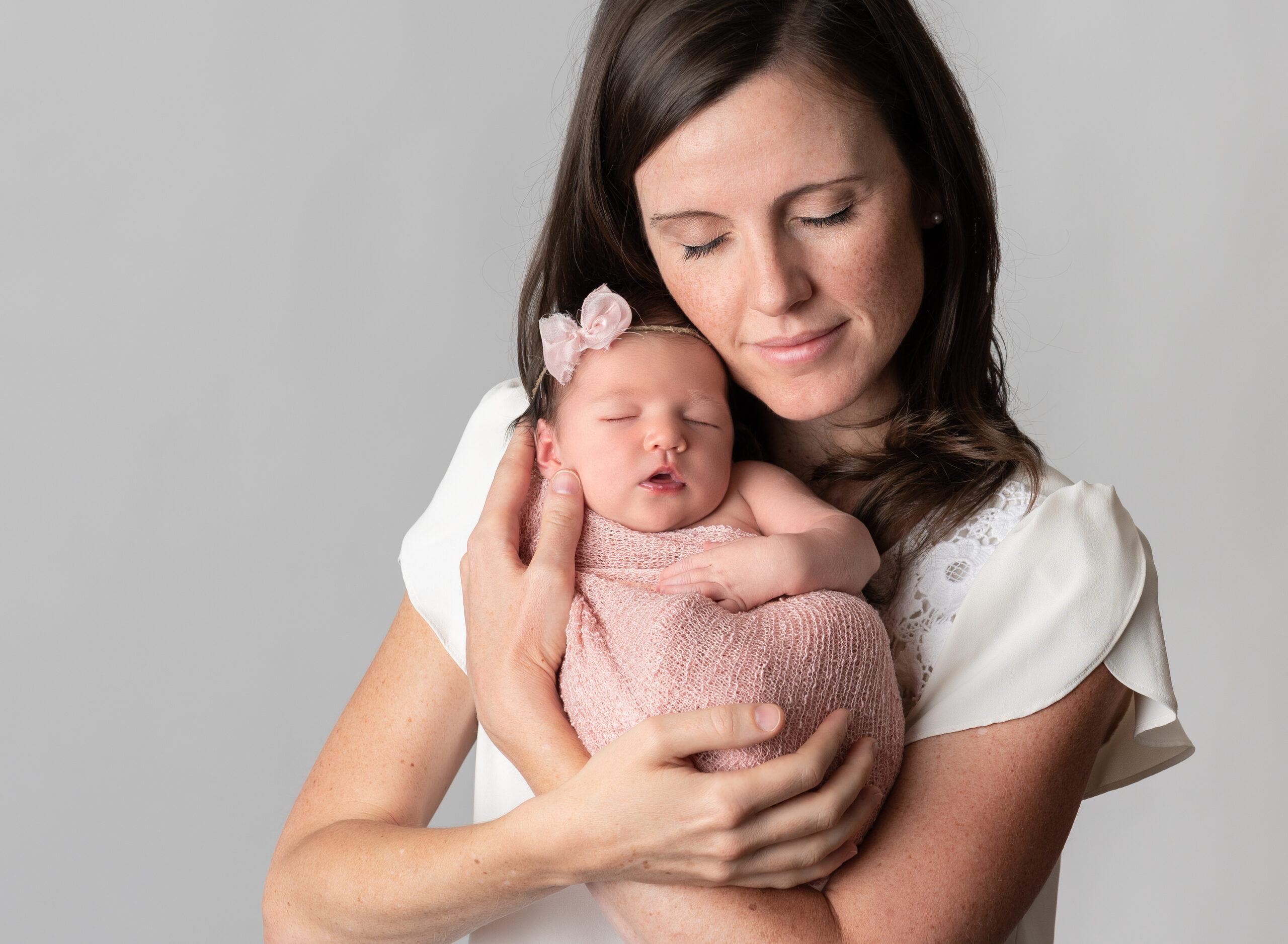 mom snuggling her newborn baby girl at their professional newborn photos in Chicago