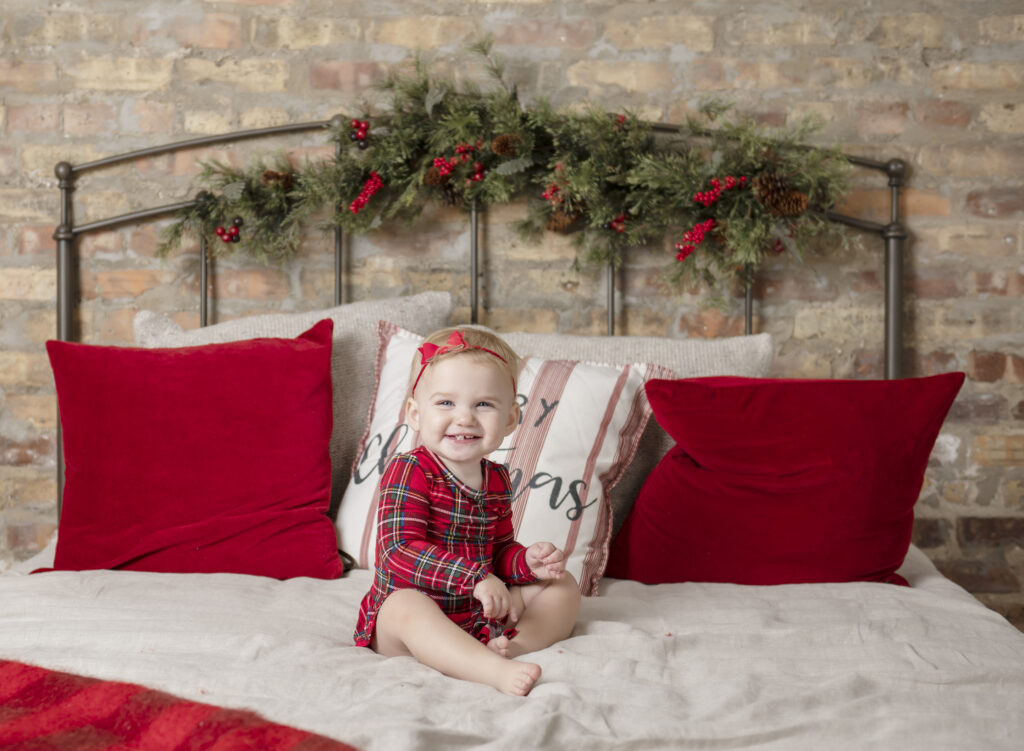 Young girl sitting on a bed decorated in a holiday theme.