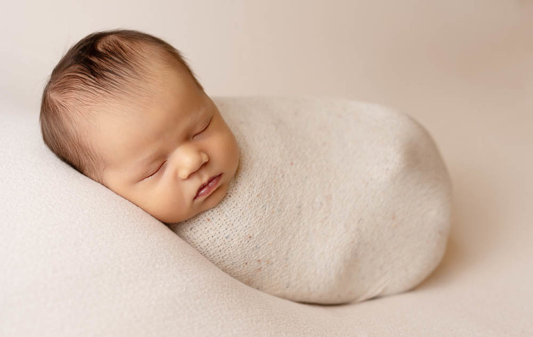 newborn boy in cream swaddle